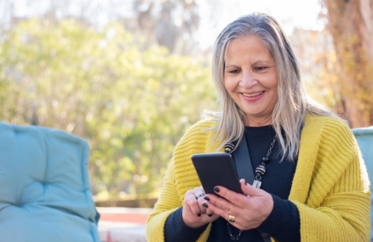 donna che sorride mentre legge qualcosa sul cellulare