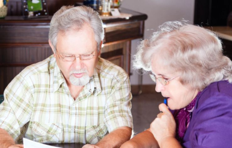 uomo e donna anziani seduti ad un tavolo mentre leggono un foglio