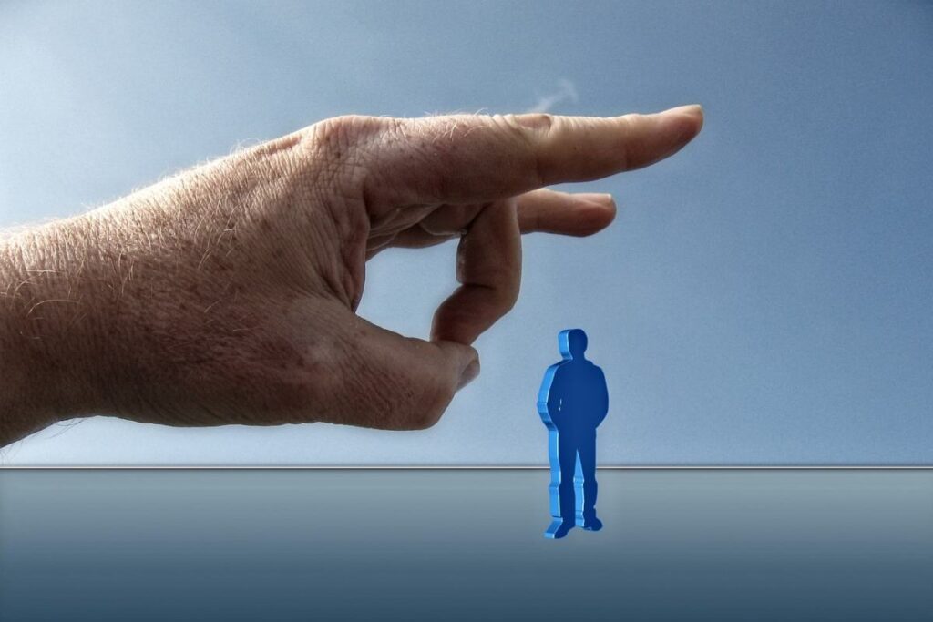 mano che con due dita scaccia via un uomo in miniatura