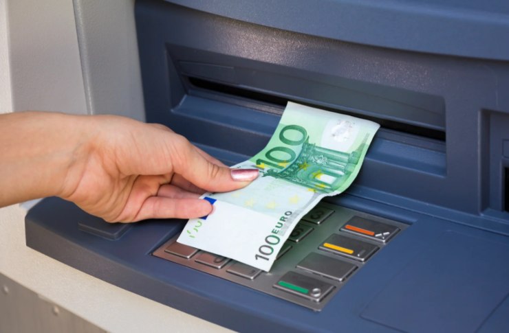 donna che preleva una banconota da 100 euro allo sportello automatico