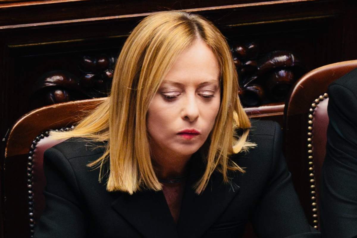 giorgia meloni seduta in parlamento con lo sguardo basso