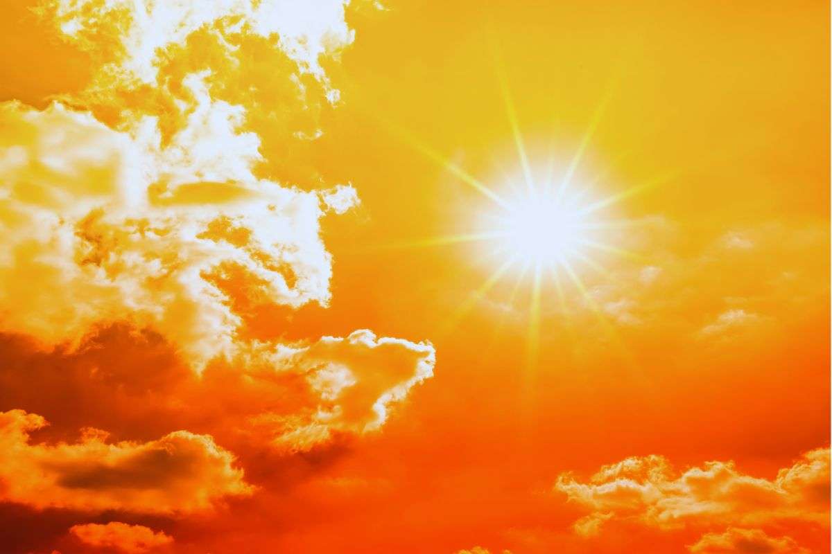 Sole che splende in alto su un cielo color arancione