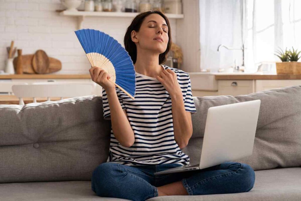 Donna che sventola un ventaglio contro il caldo in casa