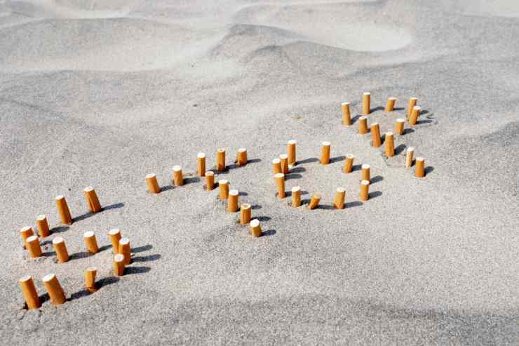 scritta stop sulla sabbia formata con mozziconi di sigarette simbolo del divieto di fumo in spiaggia in Abruzzo