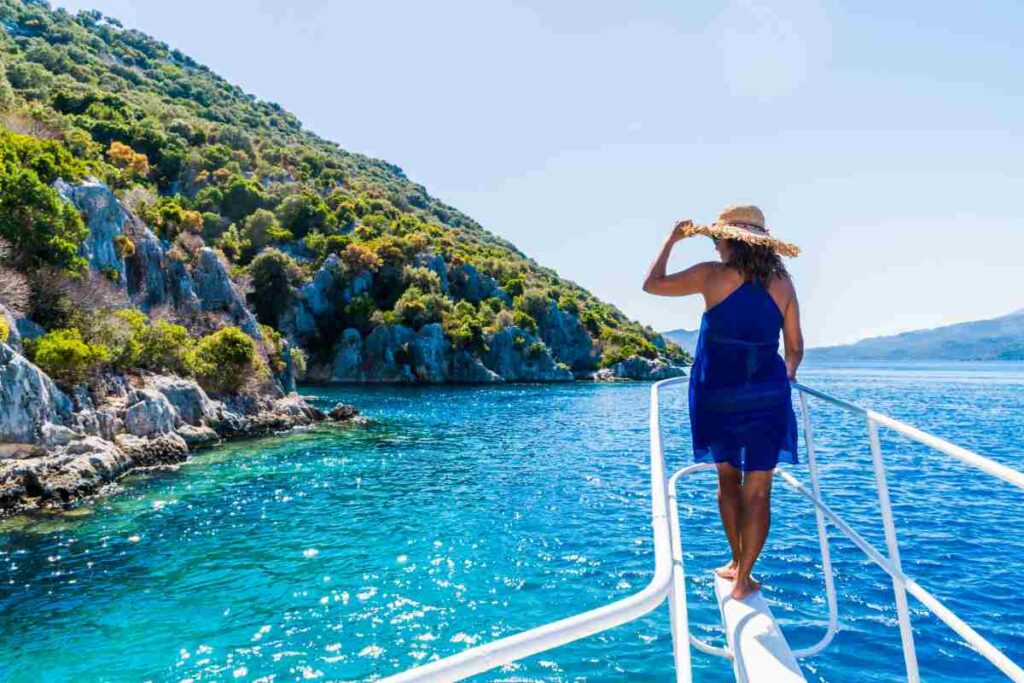 donna su una barca ammira la bellezza della costa