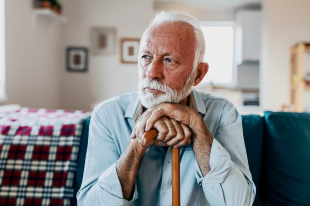 uomo anziano seduto sul divano che si appoggia ad un bastone
