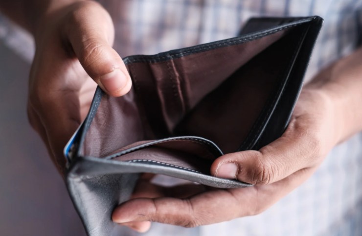 uomo che tiene in mano un portafoglio vuoto