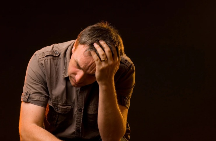 uomo preoccupato con una mano sulla testa