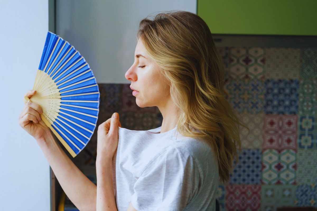 Donna accaldata che utilizza il ventaglio per rinfrescarsi