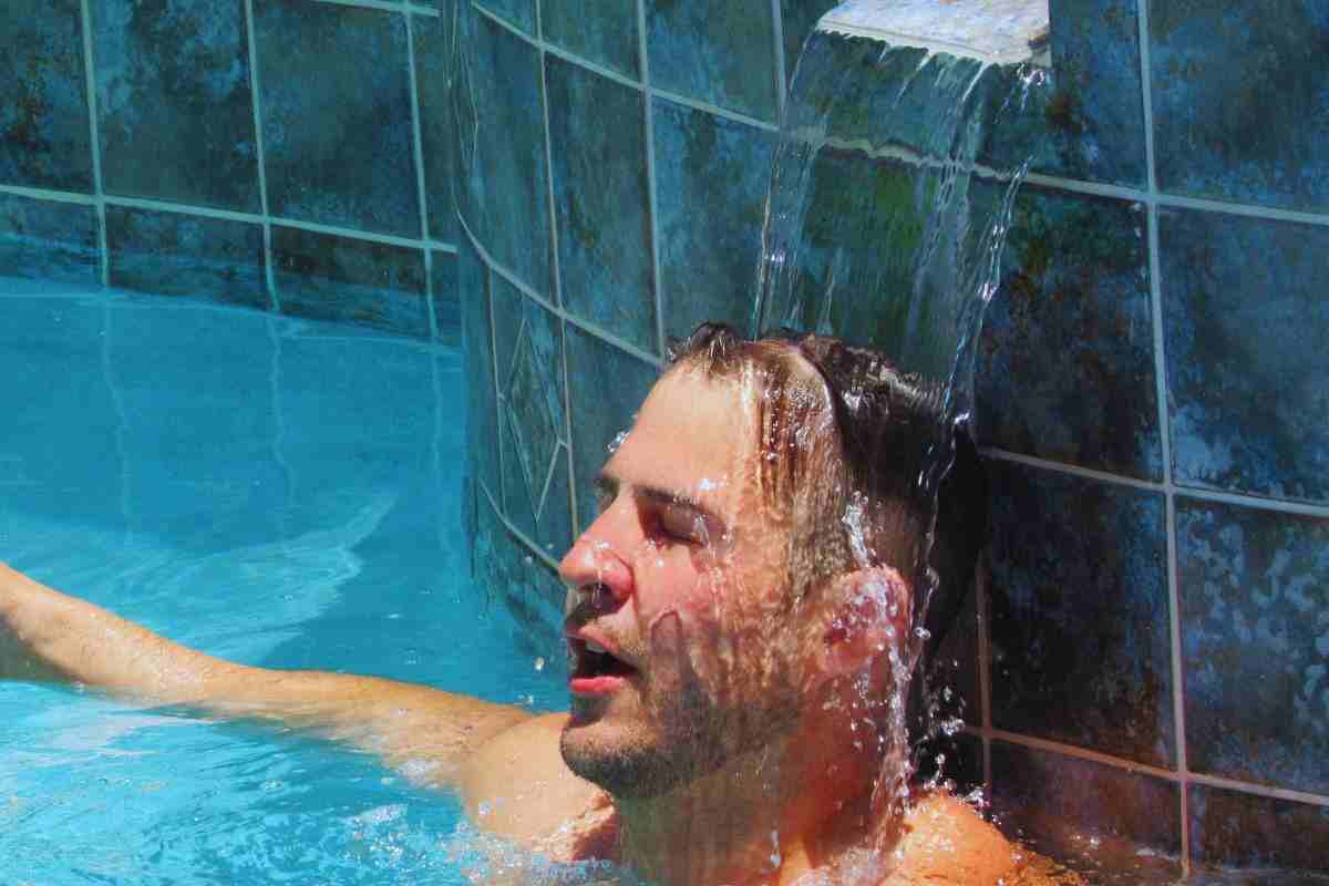 uomo che trova refrigerio sotto un getto d'acqua