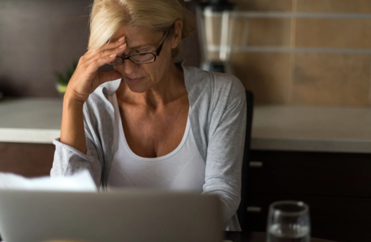donna preoccupata con una mano sulla fronte seduta davanti al computer