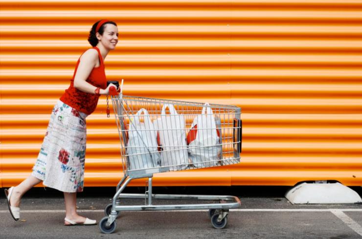donna che spinge un carrello pieno di sacchetti della spesa