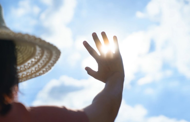 donna si scherma dal sole con una mano