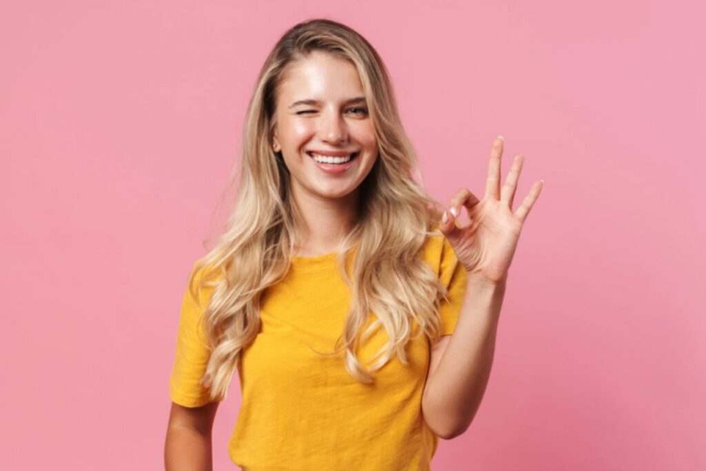 donna sorridente che strizza l'occhio e fa ok con le dita