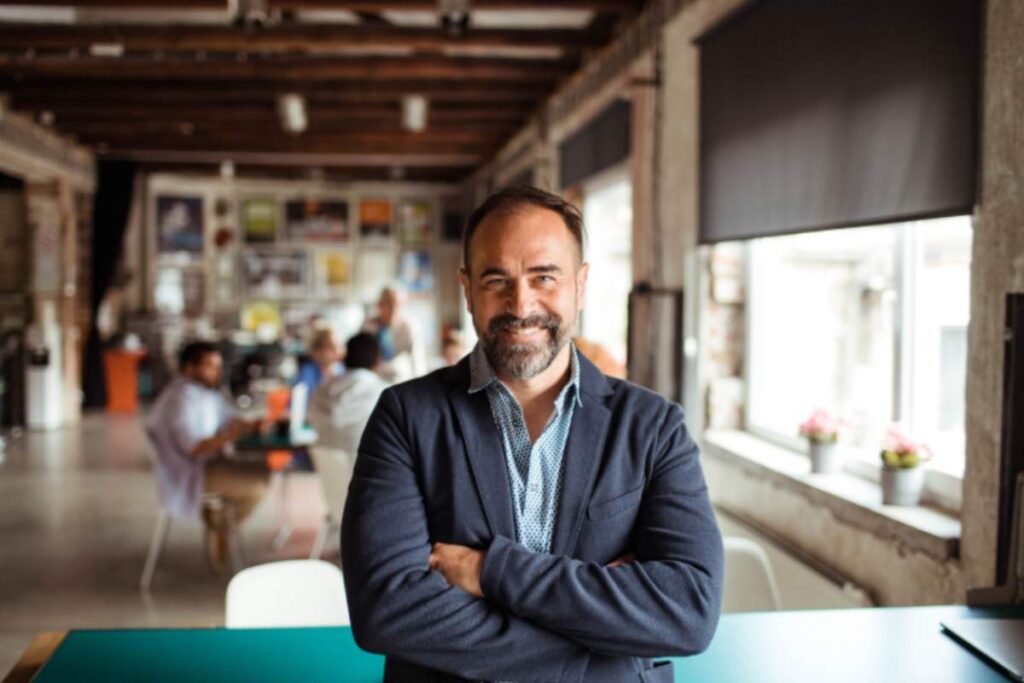 uomo che sorride e dietro di lui altre persone che lavorano