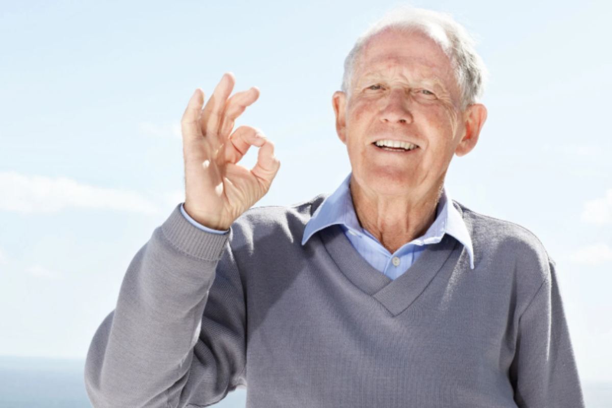 uomo anziano che sorride e fa ok con le dita
