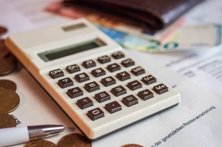 calcolatrice sul tavolo con penna e soldi