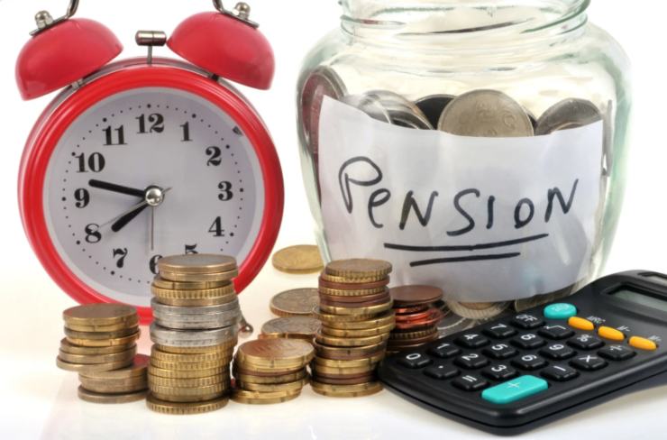 barattolo pieno di monete accanto ad una sveglia e ad una calcolatrice