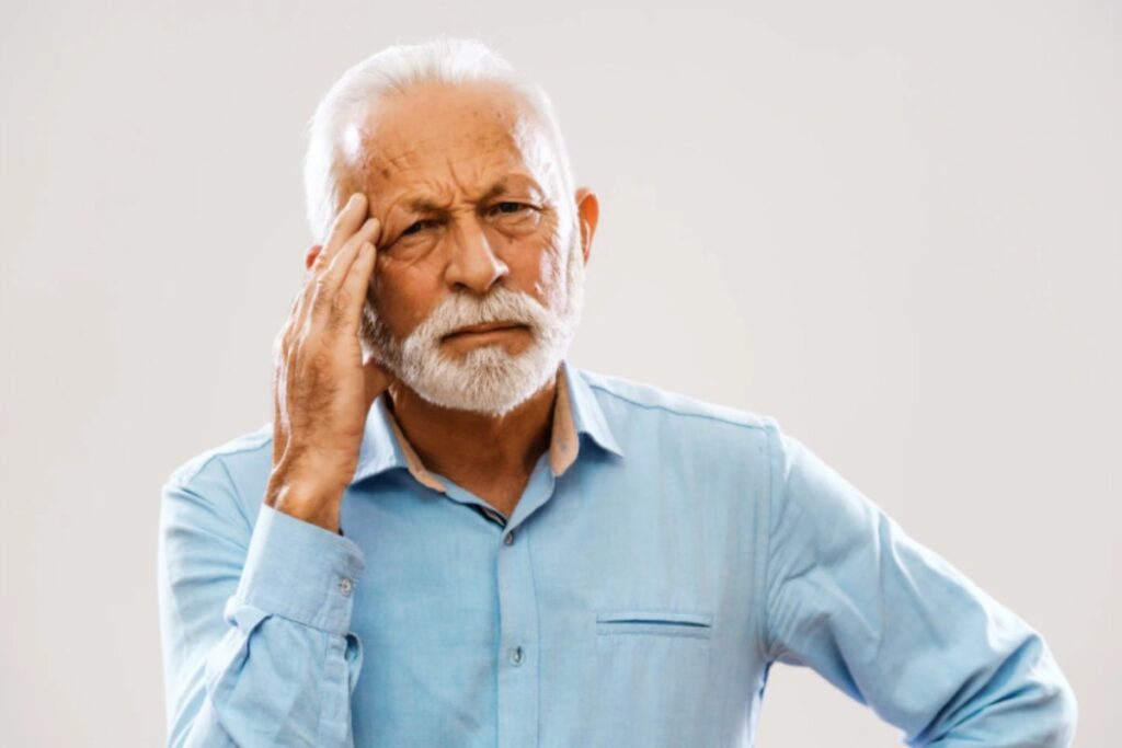 uomo anziano preoccupato con una mano su una tempia
