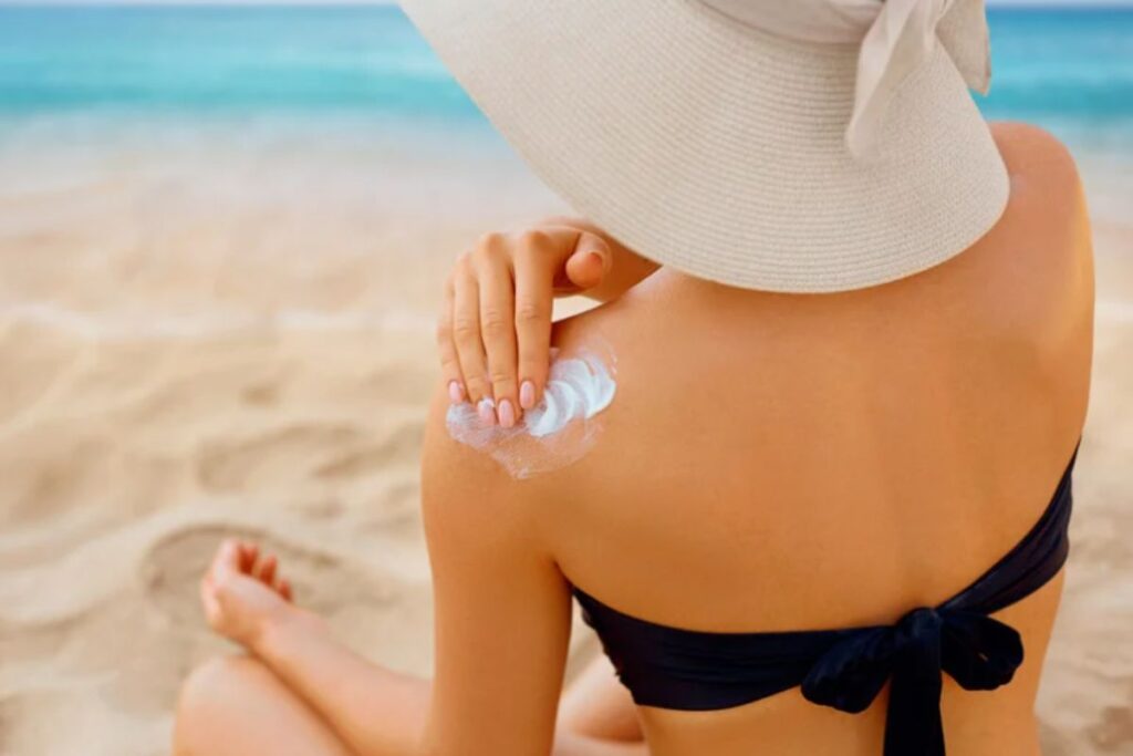 donna in spiaggia si spalma protezione solare