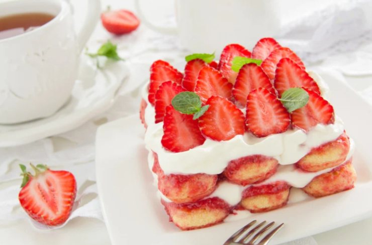 tiramisù con fragole e panna in un piatto con forchetta