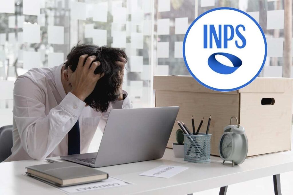 uomo con le mani in testa seduto alla scrivania con pc e scatolone