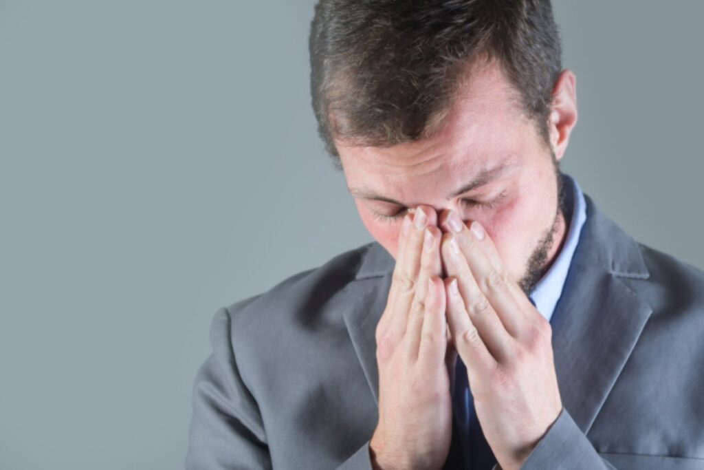 uomo preoccupato con occhi chiusi e mani sulla faccia