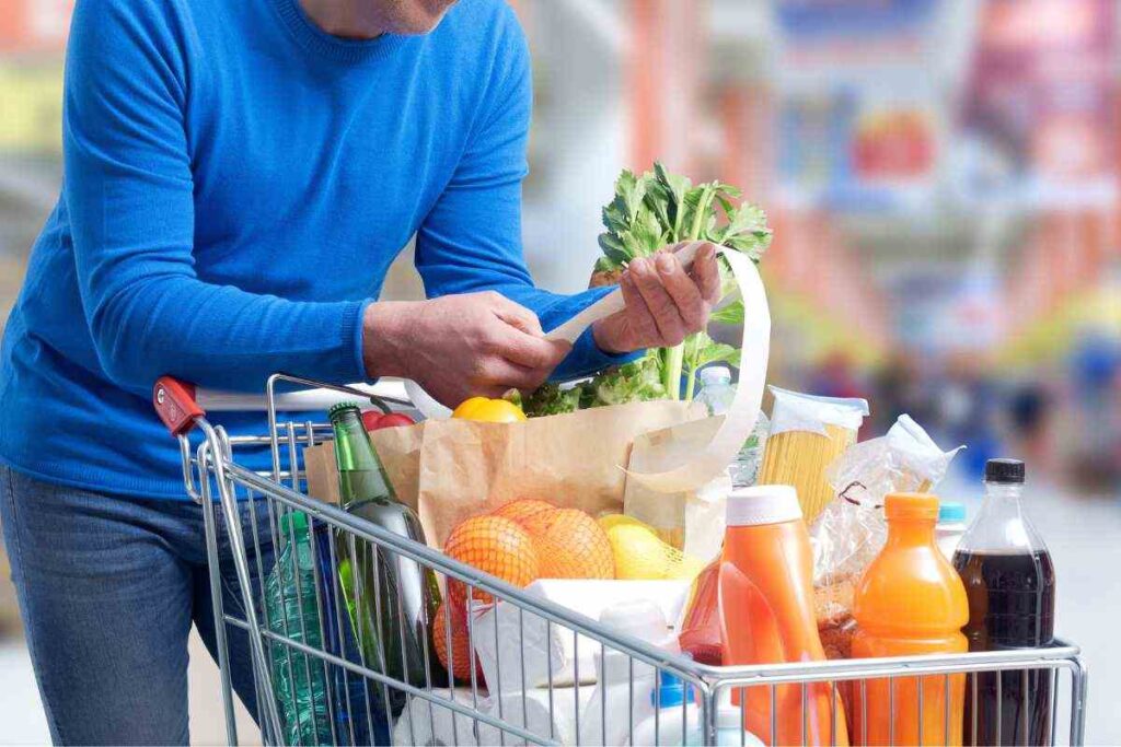 persona guarda lo scontrino con carrello pieno