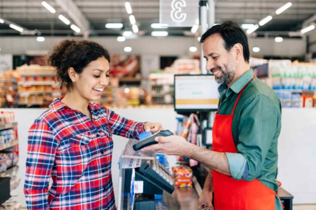 donna felice che paga alla cassa del supermercato