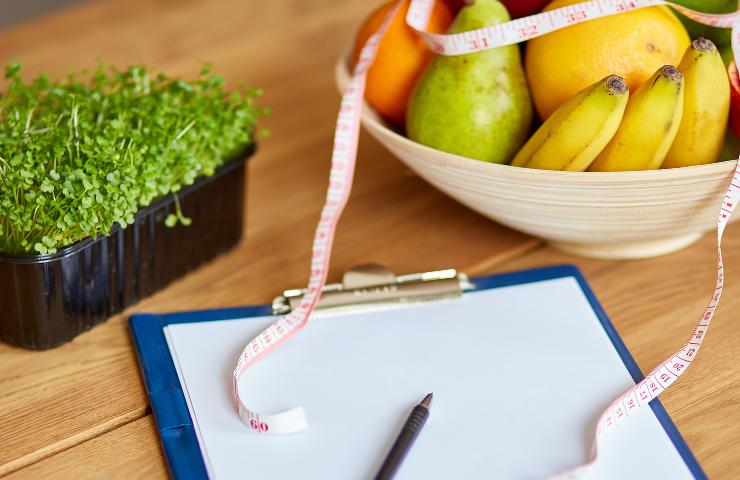 Frutta e verdura e la cartellina di un nutrizionista con un metro
