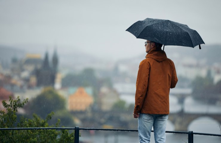 Un uomo sotto alla pioggia con l'ombrello