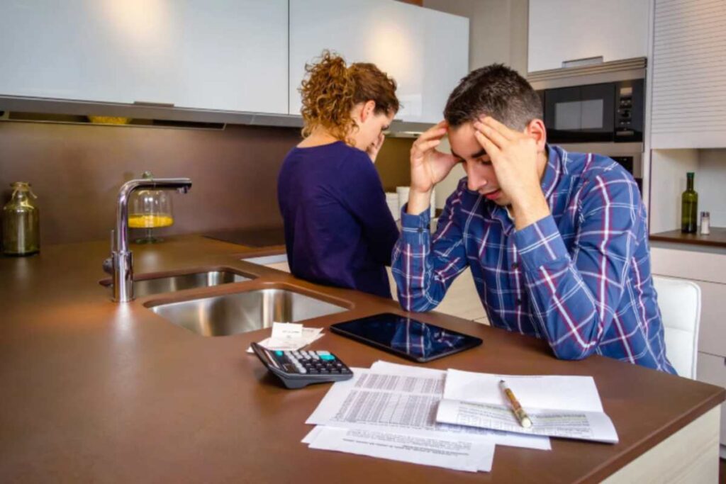 uomo e donna disperati in cucina con una calcolatrice e dei fogli