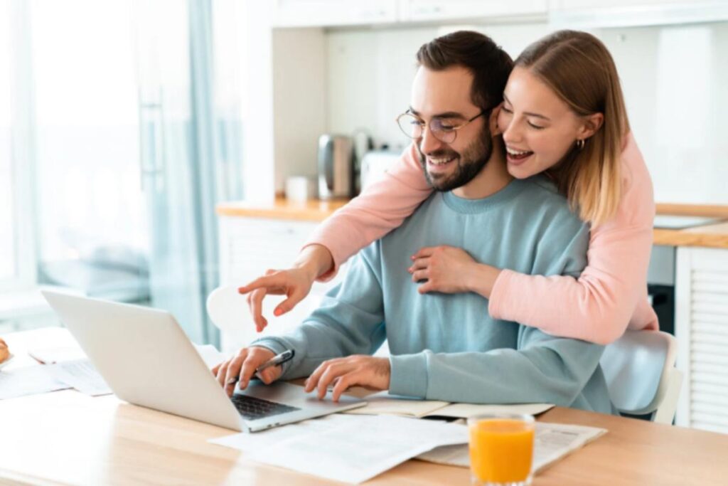 coppia che sorride mentre guarda una cosa al computer