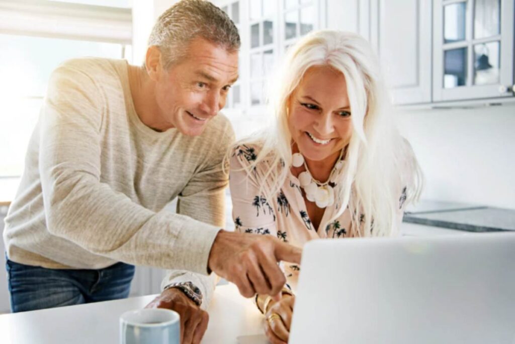 uomo e donna che sorridono mentre guardano qualcosa sul computer