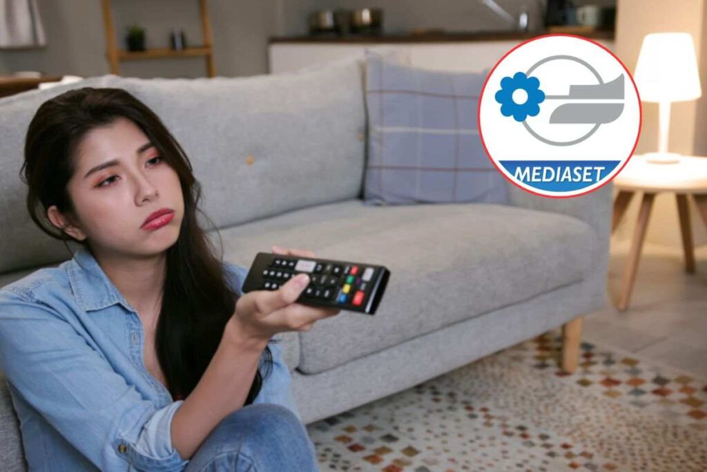 donna scocciata mentre guarda tv e logo mediaset