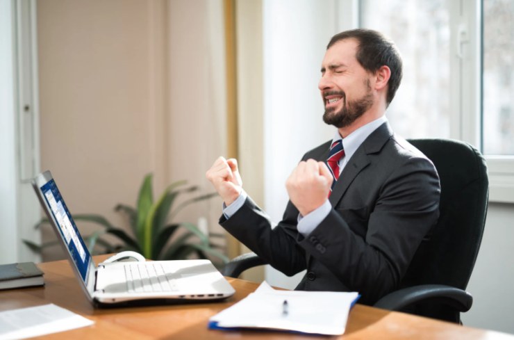 uomo che esulta seduto davanti al computer
