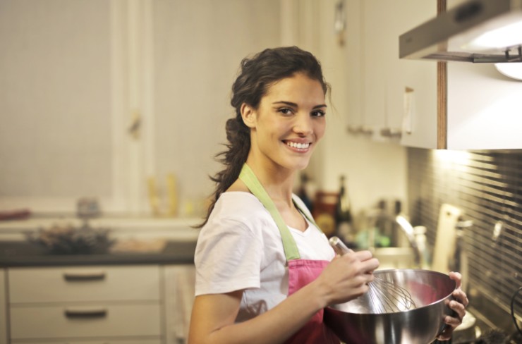 donna che sorride con una ciotola e una frusta in mano