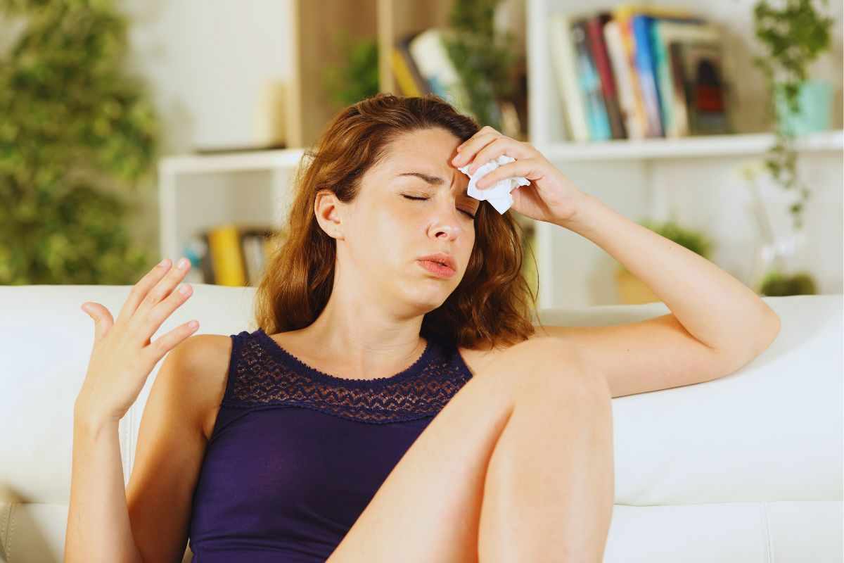 Giovane donna che asciuga il sudore dalla fronte con fazzoletto