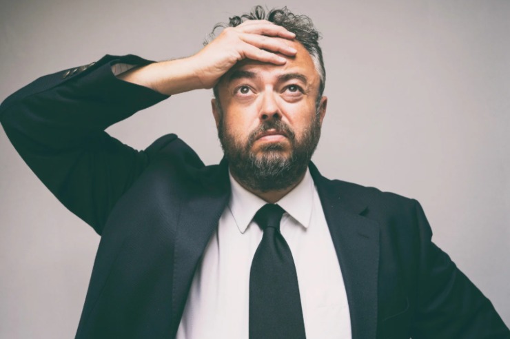 uomo preoccupato con una mano sulla fronte