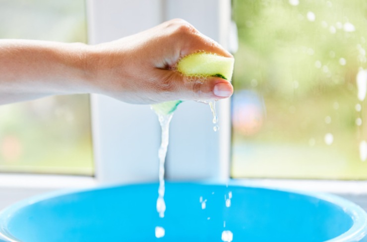 mano strizza spugna con sapone in secchio