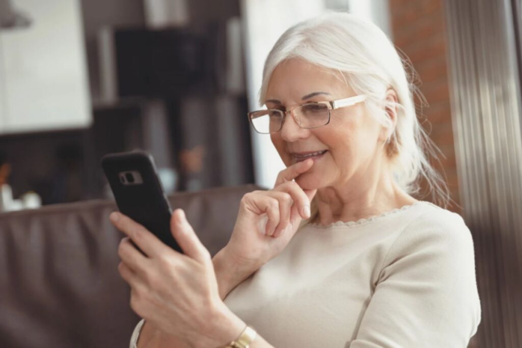 donna anziana che sorride mentre guarda il cellulare