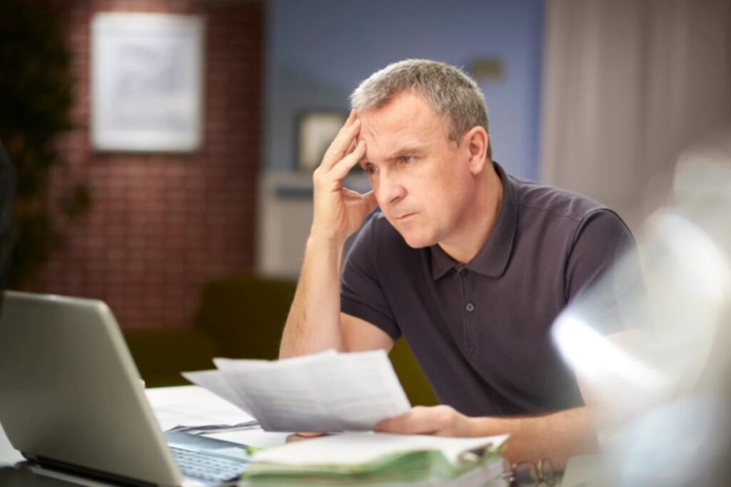 uomo seduto davanti al computer con una mano sulla fronte