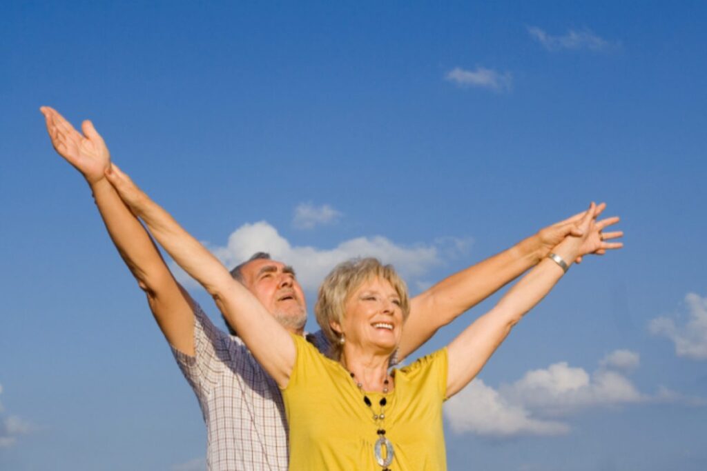 coppia di anziani felici con le braccia verso l'alto