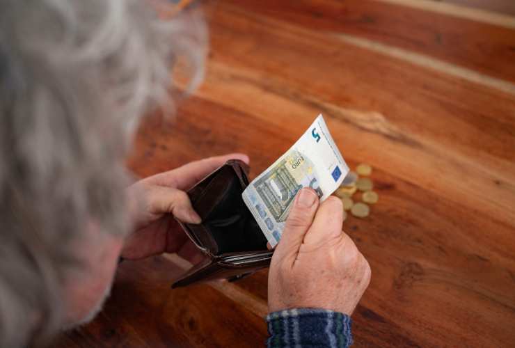 donna di spalle mette i soldi nel portafoglio