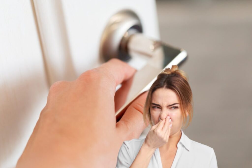 mano che apre porta e donna che sente puzza