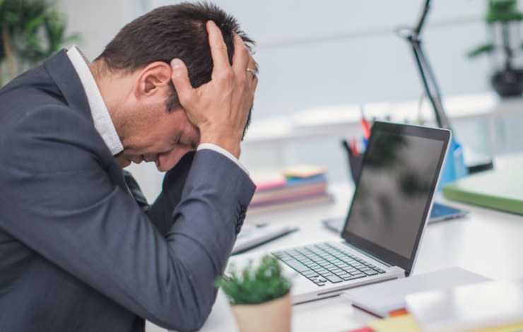 uomo seduto alla scrivania con la testa tra le mani