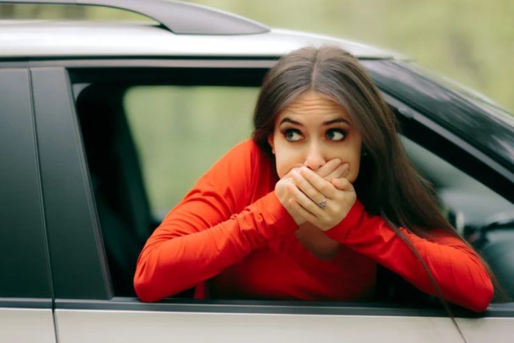 donna che si sporge dall'auto per la nausea