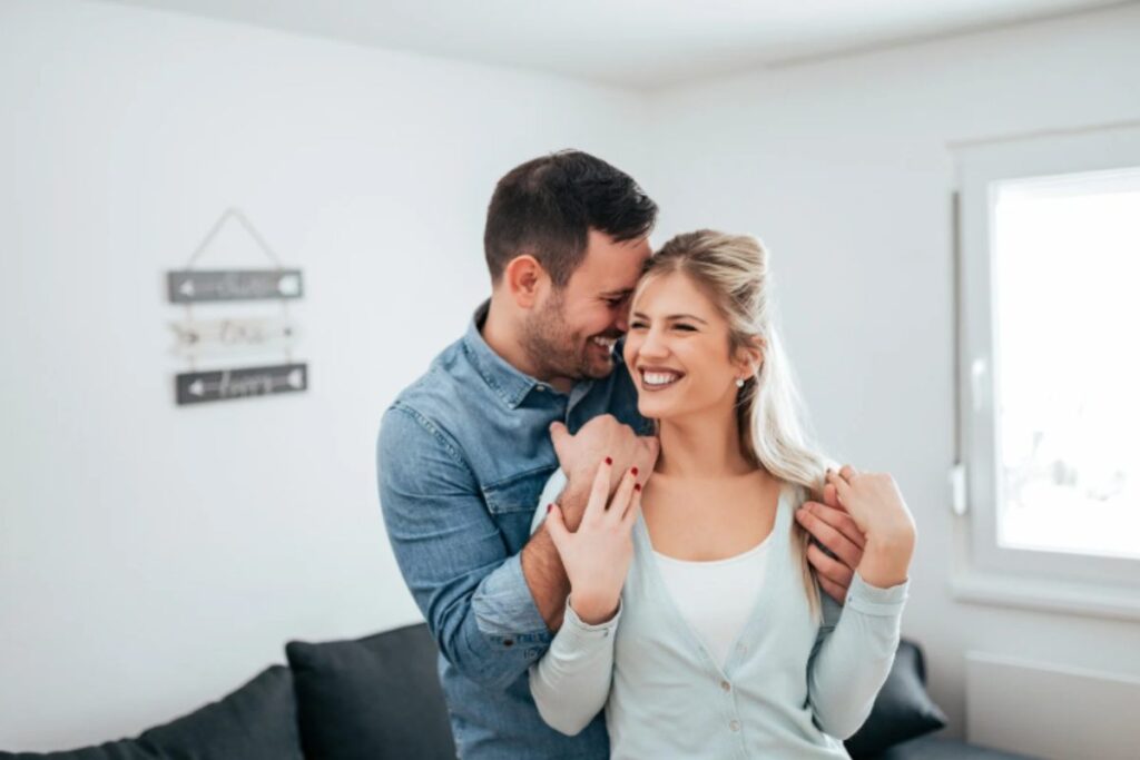 uomo e donna abbracciati che sorridono in salotto
