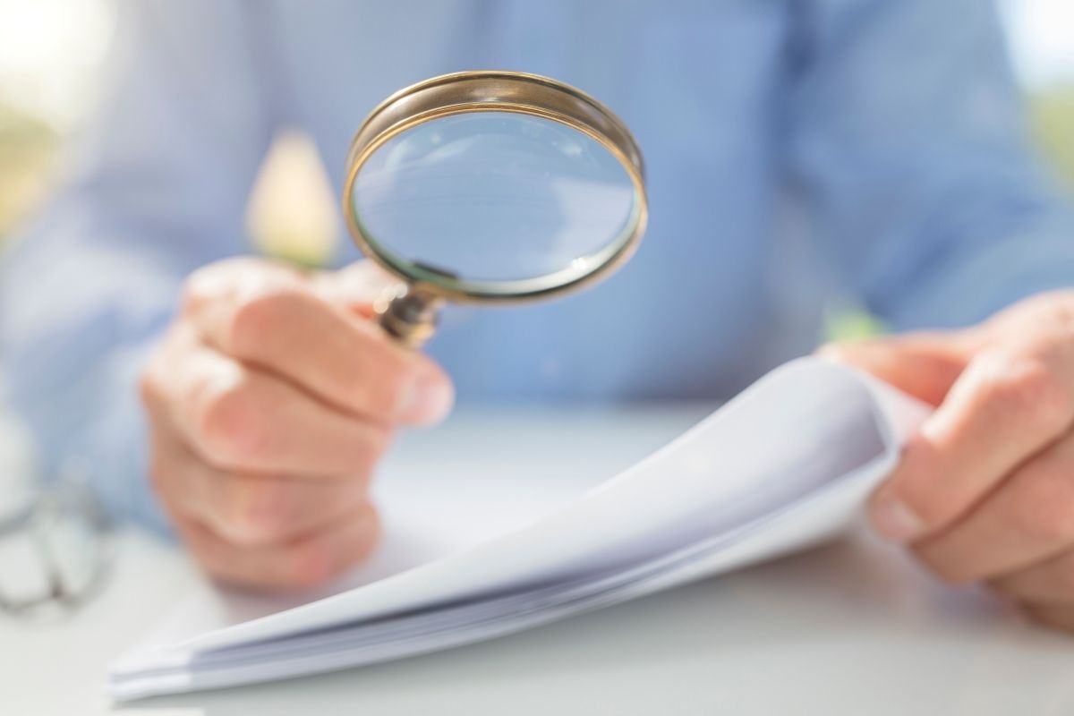 Uomo controlla documenti con lente ingrandimento