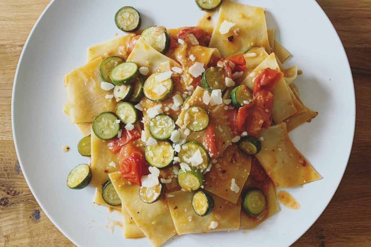 piatto fumante di maltagliati con zucchine, pomodorini e formaggio grattugiato